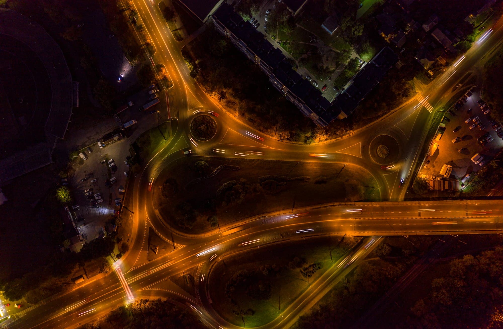 Un enlace de autopista fotografiado desde el aire de noche, con las estelas de los faros marcando cada ramal.
