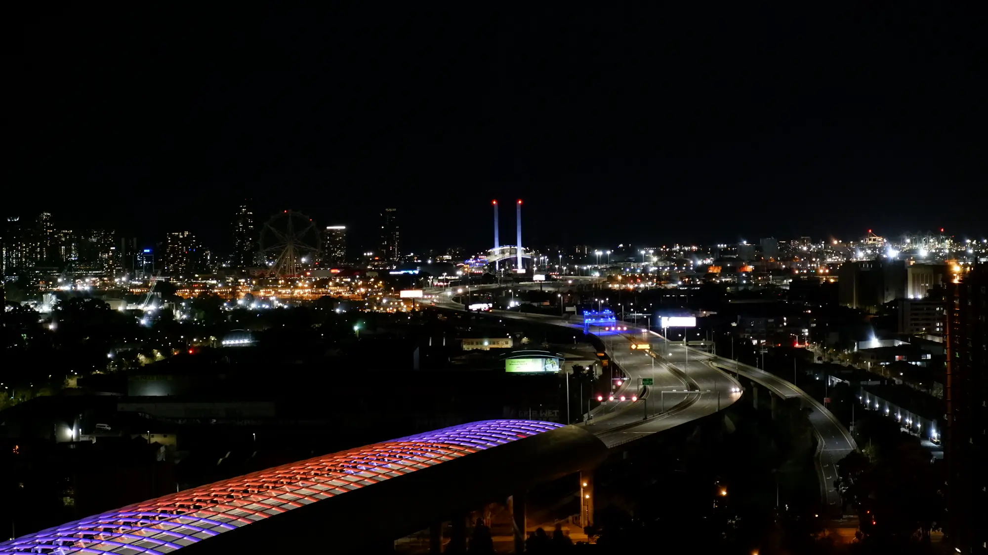 Una ciudad de noche vista desde lo alto, con su autopista elevada