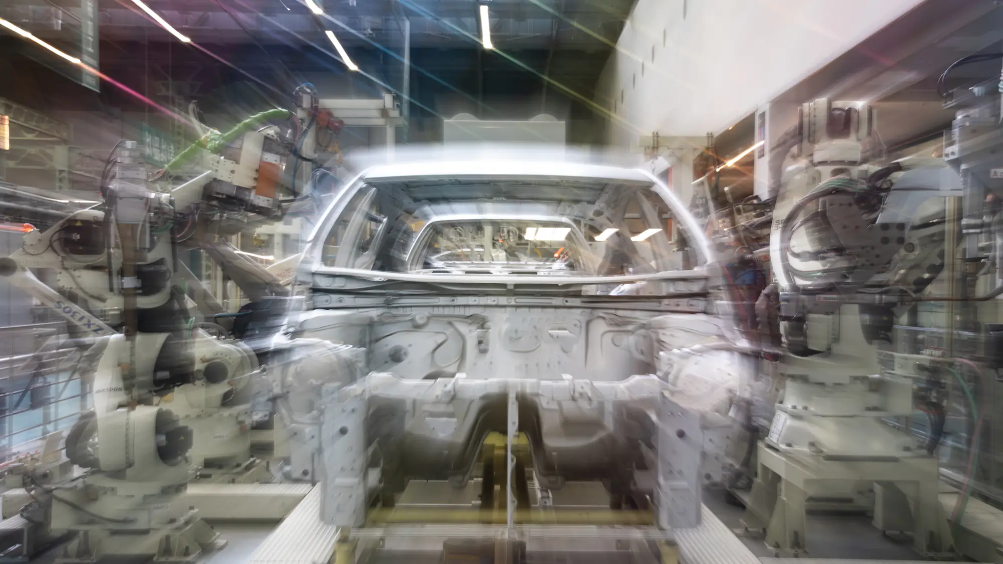 Una carrocería en una línea de montaje, entre brazos robóticos