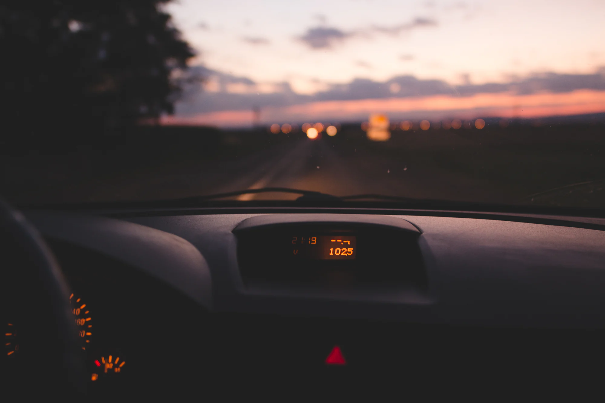 El salpicadero de un coche al anochecer, con la carretera delante