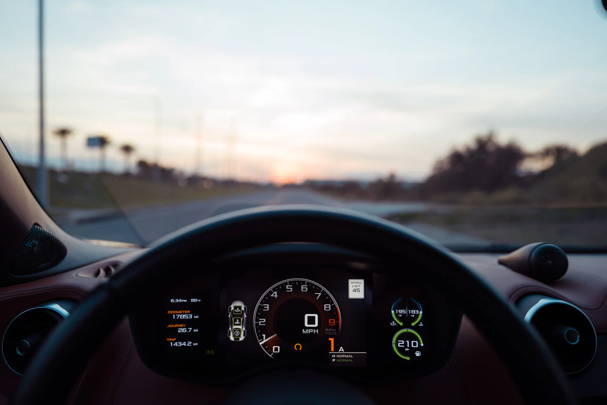 El cuadro de instrumentos digital de un coche, con la carretera delante al anochecer